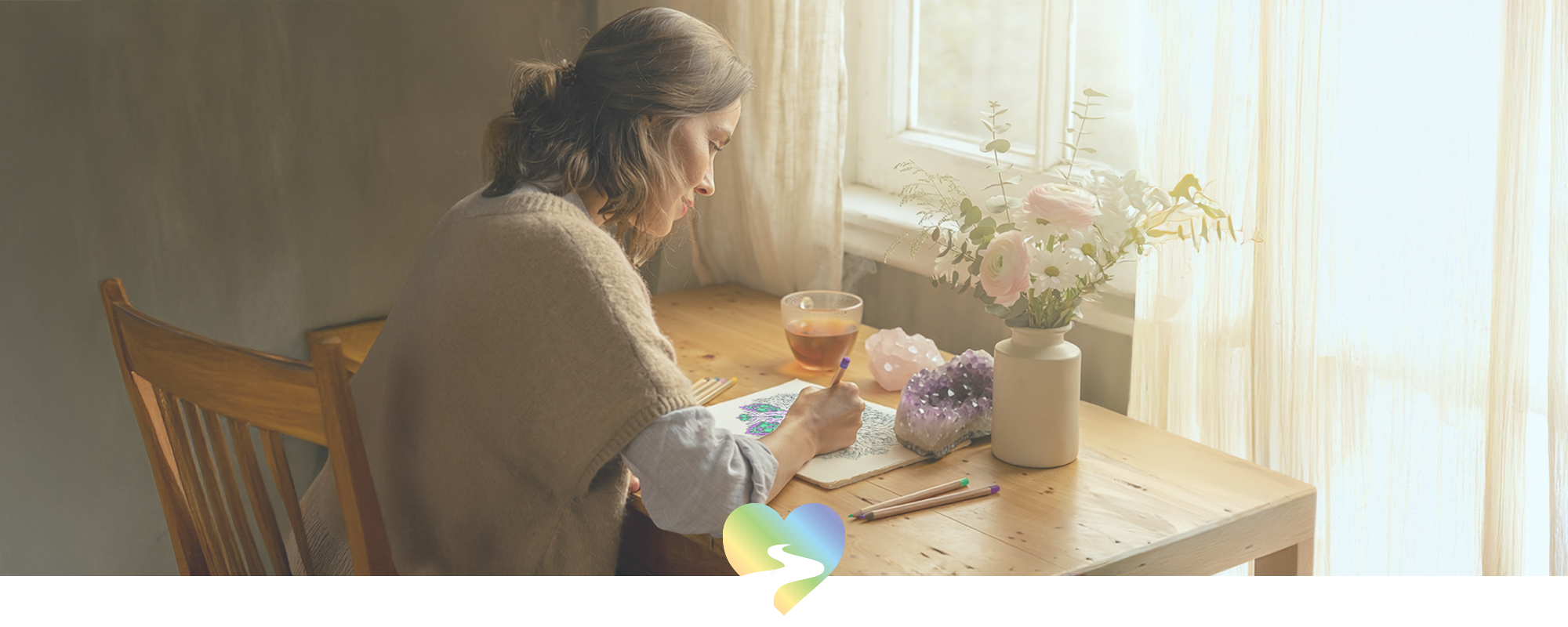 Woman mindfully colouring at a sunlit table with flowers, crystals, and a cup of tea – free download from Your Spirit Journey.