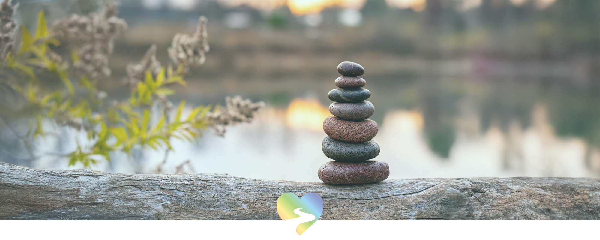 zen stacked stones on a fallen tree branch at a water