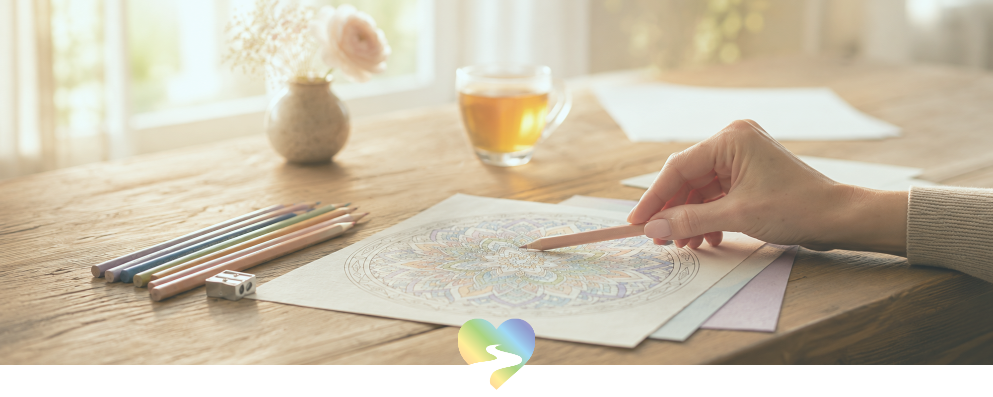 Woman colouring a mandala with coloured pencils at a wooden table in soft natural light